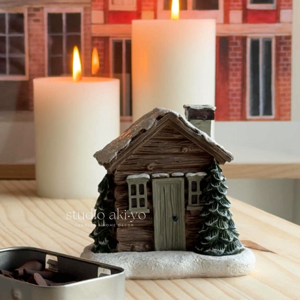 Decorative house-shaped candle holder with candles on a wooden surface.