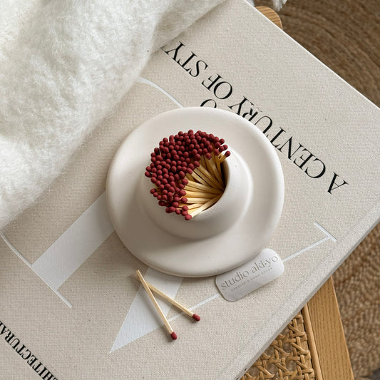 White ceramic match holder with matches on a textured surface