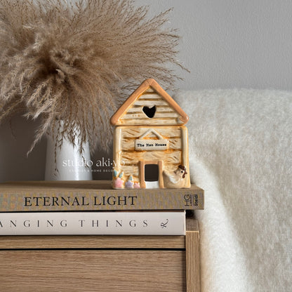 Hen house chicken coop wax melt burner on a stack of books with decorative elements.