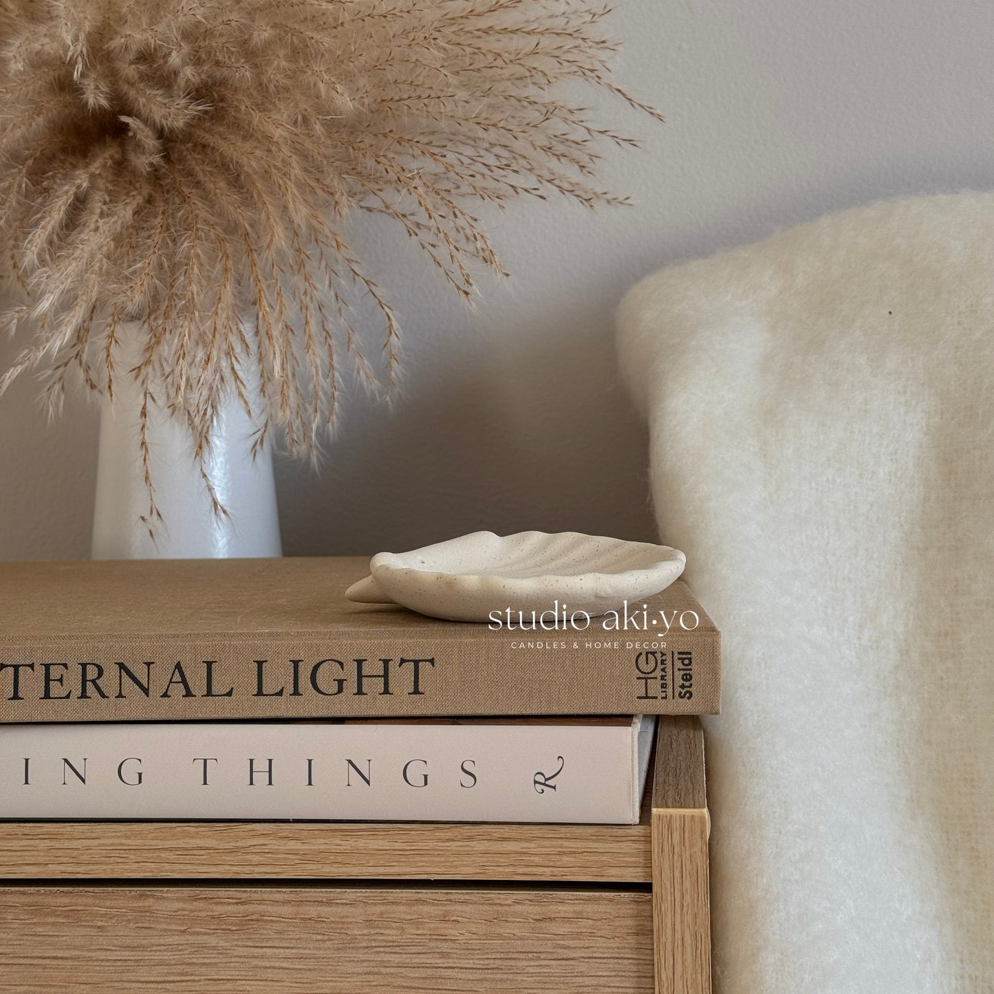 Stack of books on a wooden surface with decorative elements and 'studio aki.wo' branding.