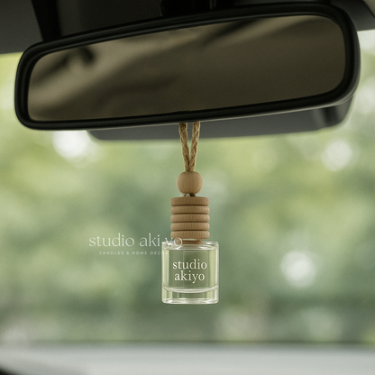 Car air freshener with 'studio akiyo' branding hanging from a car's rearview mirror.