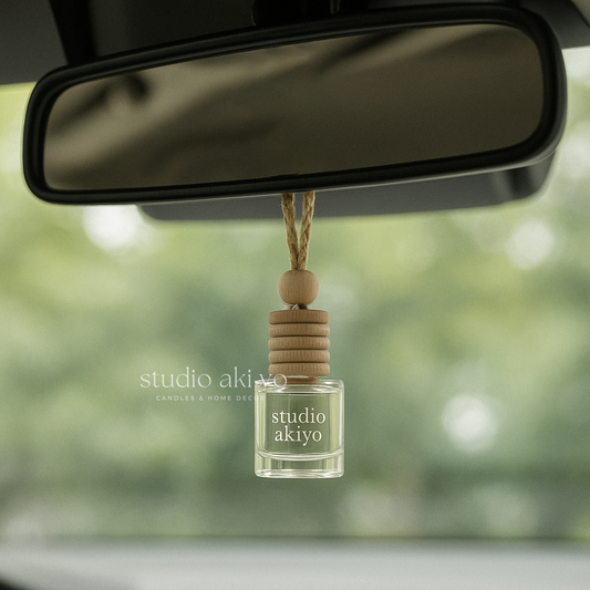 Car air freshener with 'studio akiyo' branding hanging from a car's rearview mirror.