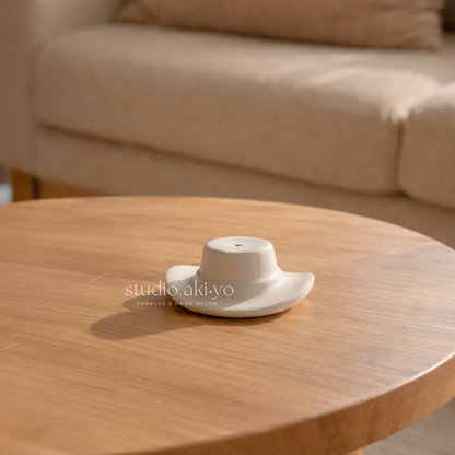 White ceramic teapot on a wooden table with a blurred beige sofa in the background