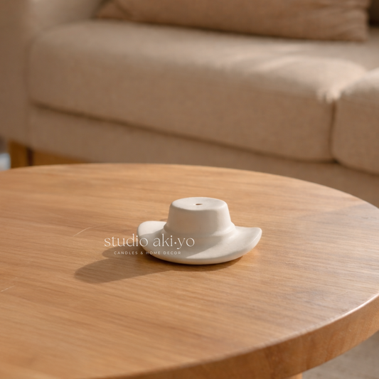 White ceramic teapot on a wooden table with a blurred beige sofa in the background