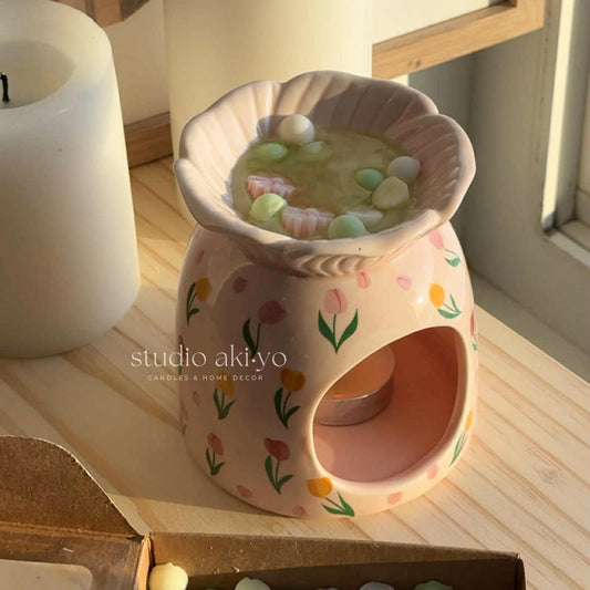 Floral-patterned wax warmer on a stack of books with decorative plants in the background