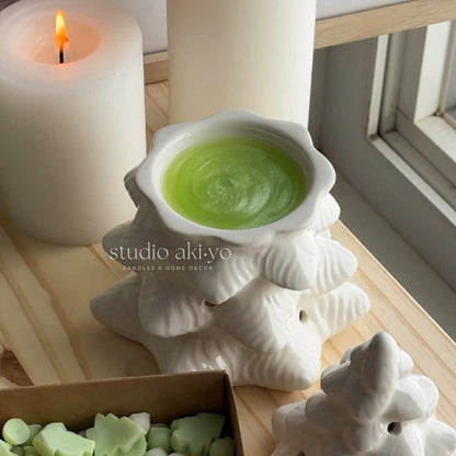 White ceramic Christmas tree ornament on a stack of books with a neutral background